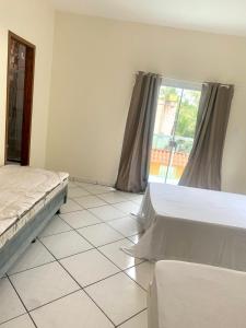 a bedroom with two beds and a large window at CASA DE PRAIA COM PISCINA EM ILHÉUS-BA a 50m DA PRAIA in Ilhéus +19 photos