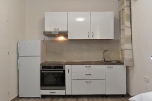 a kitchen with white cabinets and a sink and a refrigerator at SOFIA'S Studio & Room in Zadar +47 photos