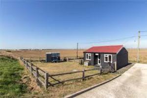 a small building with a red roof next to a fence at Beachside Bliss Cosy Cottage Jurys Gap in Rye