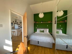 two beds in a bedroom with green walls at Beachside Bliss Cosy Cottage Jurys Gap in Rye