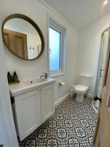 a bathroom with a sink and a mirror and a toilet at Beachside Bliss Cosy Cottage Jurys Gap in Rye