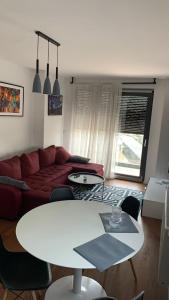 een woonkamer met een witte tafel en een rode bank bij Penthause StAnto, novogradnja, blizina Maksimira in Zagreb