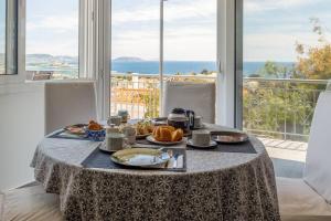 a table with food on it in front of a window at Bunny island- seaview house, private garden , Lagonisi, Attika riviera in Kalívia Thorikoú
