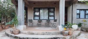 a porch of a house with chairs and plants at Kalahari Sand Ridge Inn in Livingstone