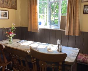 a dining room table with chairs and a window at Kings Head Low House in Laxfield