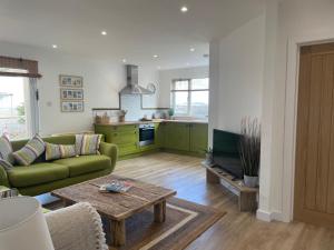 a living room with a green couch and a table at Normans Bay Charm The Crabshack Cottage in Pevensey