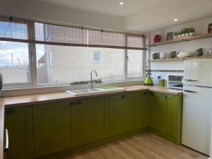 a kitchen with green cabinets and a white refrigerator at Normans Bay Charm The Crabshack Cottage in Pevensey