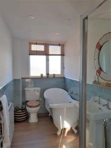 a bathroom with a tub and a toilet and a sink at Normans Bay Charm The Crabshack Cottage in Pevensey