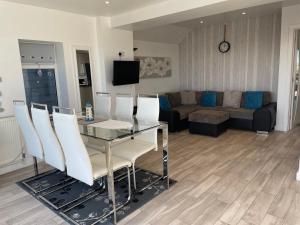 a living room with a glass table and white chairs at Beachfront Bliss Stylish Retreat in Pevensey