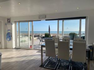 a dining room with a table and a view of the ocean at Beachfront Bliss Stylish Retreat in Pevensey