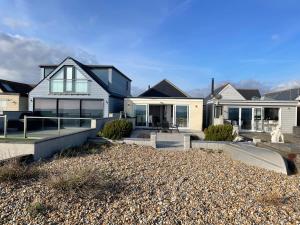 a house on the beach with a driveway at Beachfront Bliss Stylish Retreat in Pevensey