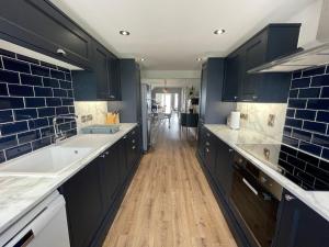 a kitchen with black cabinets and a wooden floor at Luxury Beachfront The Cozy Clam in Pevensey