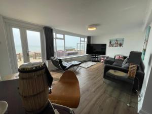 a living room with a couch and a television at Luxury Beachfront The Cozy Clam in Pevensey