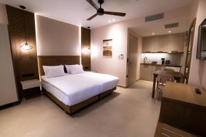 a bedroom with a white bed and a kitchen at Nissos Apartments in Mirina