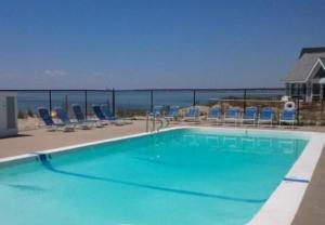 a swimming pool with chairs and the ocean in the background at Horizons Beach Resort in North Truro