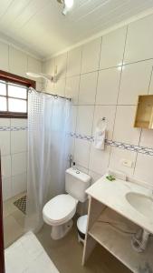 a white bathroom with a toilet and a sink at Pousada Brisa do Leste in Paraty