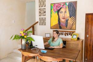 une femme assise sur un bureau avec un ordinateur portable dans l'établissement Hotel Siesta Holbox, à Holbox