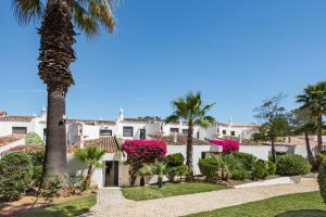 una grande casa bianca con palme e fiori rosa di Victory Village Beach Villa - Quinta do Lago a Quinta do Lago