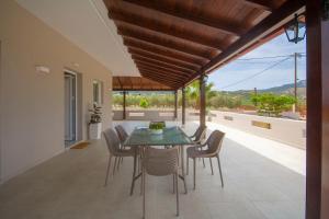 a dining room with a table and chairs on a patio at Villa Kalliestia, sea view veranda and garden in Kissamos