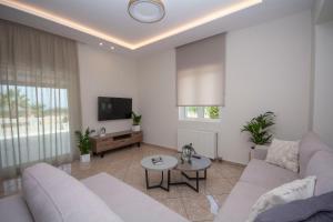 a living room with a couch and a tv at Villa Kalliestia, sea view veranda and garden in Kissamos