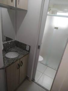 uma casa de banho com um lavatório e uma cabina de duche em vidro. em Apartamento Relaxante próximo ao aeroporto em São José dos Pinhais