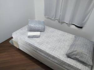 uma pequena cama com duas toalhas e uma janela em Apartamento Relaxante próximo ao aeroporto em São José dos Pinhais