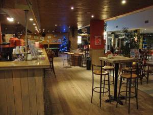 un restaurante con bar y taburetes en una habitación en Het Toeval, en Koksijde
