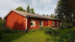 czerwony dom w ogródku obok pola w obiekcie Talo Porokylä - Nurmes w mieście Nurmes