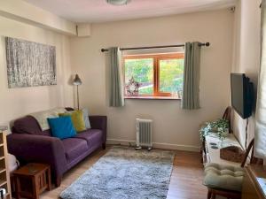 a living room with a purple couch and a window at Pass the Keys The Pumphouse Holiday Cottage in Kidwelly