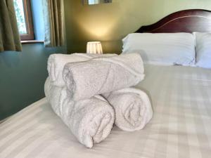 a pile of towels sitting on top of a bed at Pass the Keys The Pumphouse Holiday Cottage in Kidwelly