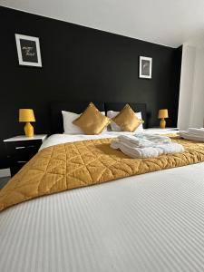 una camera da letto con un grande letto con coperte e cuscini dorati di Relocators - Parking - Central a Birmingham