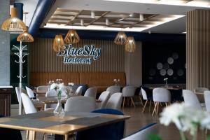 un restaurante Blue Sky con mesas y sillas blancas en Hotel Blue Sky, en Sarandë