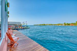 a dock with chairs and a boat in the water at Bocas Paradise Hotel in Bocas del Toro