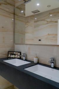 two white sinks in a bathroom with wooden walls at Hotel Blue Sky in Sarandë