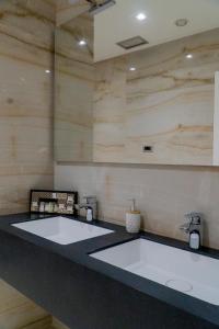 2 lavabos blancos en un baño con paredes de madera en Hotel Blue Sky, en Sarandë