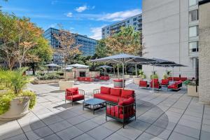 un patio con sedie rosse, tavoli e ombrelloni di Spectacular Condo at Crystal CIty With Pool/Gym ad Arlington