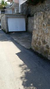 a driveway with a stone wall and a white garage at Villa Teodora in Donja Vrućica