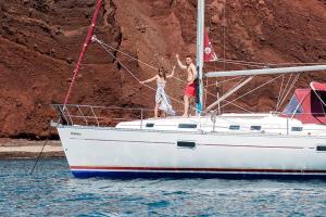 two people standing on a sail boat in the water at Orpheus in Órmos Athiniós