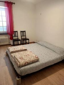 Ce lit se trouve dans un dortoir doté de 2 chaises et d'une fenêtre. dans l'établissement La Fiorita, à Bironico