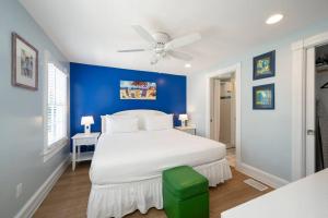 a bedroom with a white bed and a blue wall at BachelorPARTY HQ for 16-Feet to Duval-Pool-Hot tub in Key West +50 photos