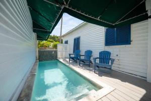 una piscina con 2 sillas azules sentadas junto a una casa en Just steps to Duval- Sleeps 10- Heated Pool House, en Key West