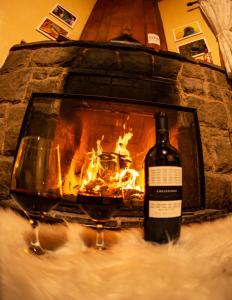 uma garrafa de vinho e dois copos em frente a uma lareira em Colônia SAA em Campos de Jordão