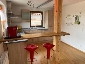 a kitchen with red stools in front of a counter at Ferienwohnung Meridiana in Tuntenhausen +43 photos