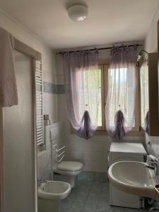 a bathroom with two sinks and a toilet and a window at Apartment-Rosella Garda in Garda