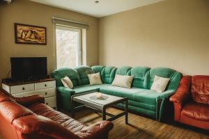 een woonkamer met een groene bank en lederen stoelen bij Contryside holiday house, for even better energy sourcing in Detva