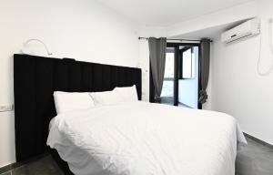 מגדלי המלכים טבריה في طبرية: غرفة نوم مع سرير أبيض مع اللوح الأمامي الأسود