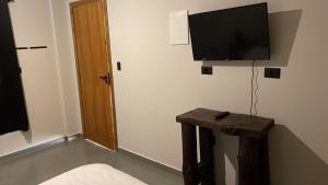 a room with a tv on the wall and a table at Studios Pinhal in Santo Antônio do Pinhal