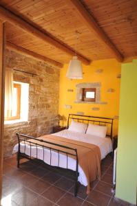uma cama num quarto com uma parede amarela em Akros Oreon Junior Suite Amori em Káto Sími