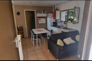 een woonkamer en een keuken met een bank en een tafel bij Petite dépendance in Isneauville
