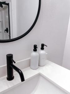 a bathroom sink with two bottles of soap and a mirror at SunStar Alaska Bed and Breakfast LLC in Anchorage